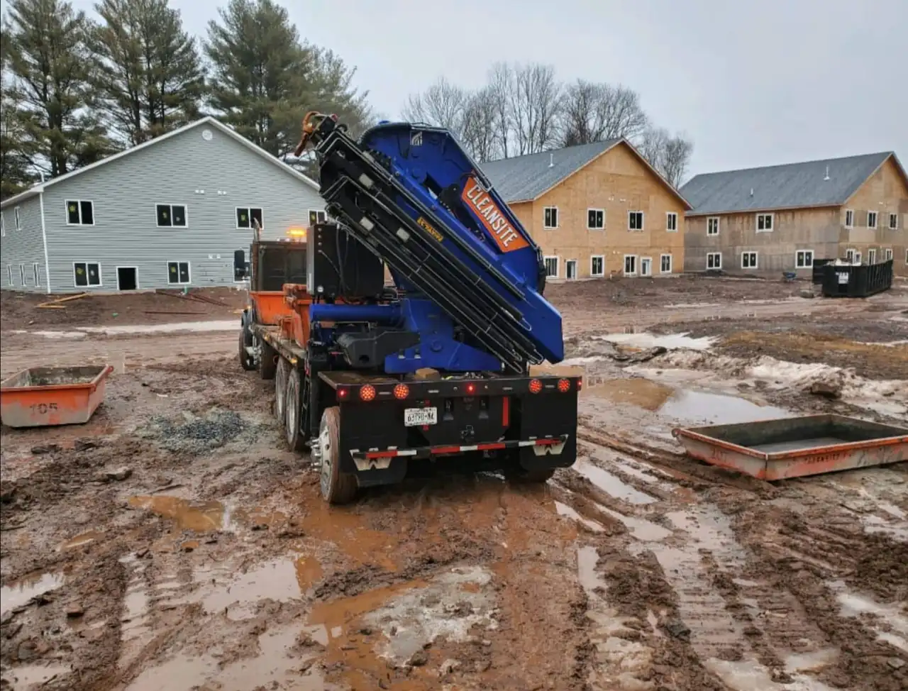 CleanSite boom truck and washout pans on a muddy housing construction site