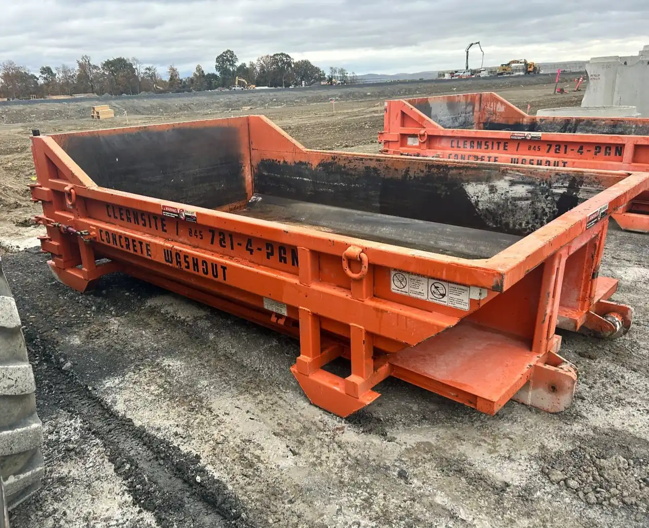 Close-up of an orange CleanSite concrete washout container on a job site