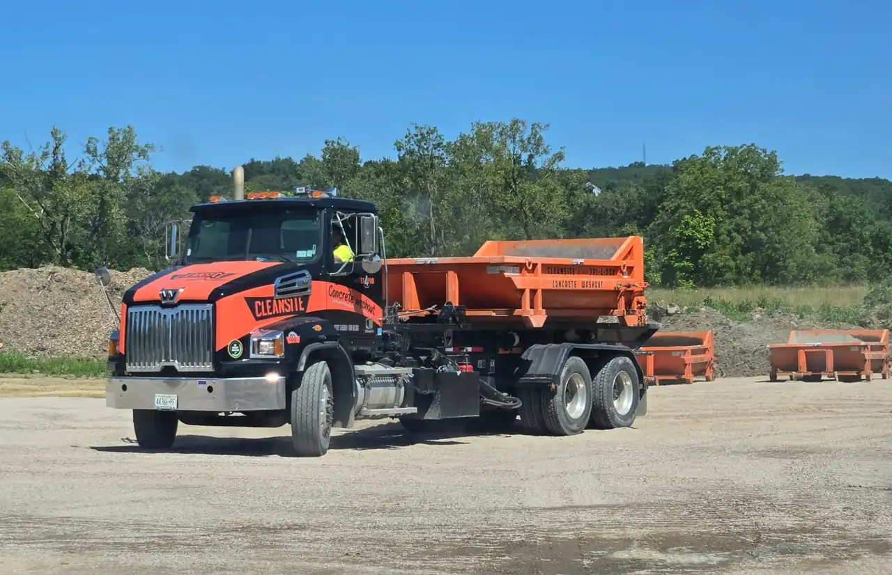 CleanSite roll-off truck carrying an orange concrete washout container on a job site