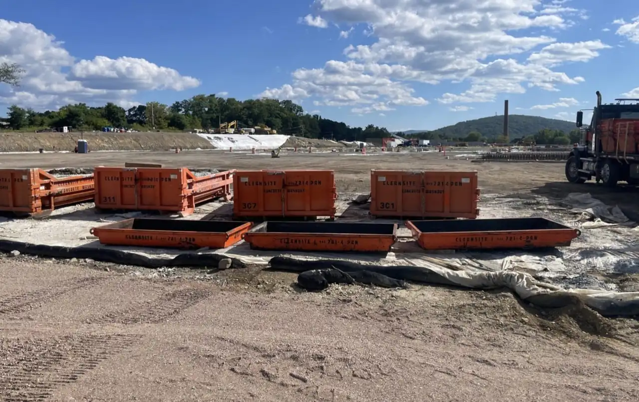 Rows of CleanSite washout containers and pans staged on a large construction site