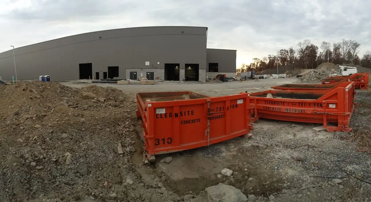 Several orange CleanSite containers lined up on a commercial construction site