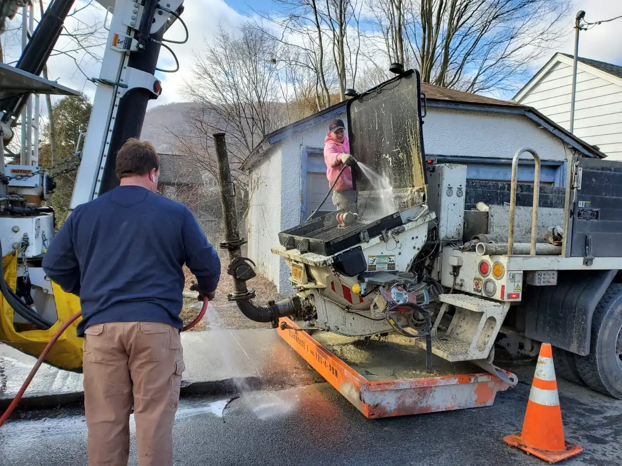 Crew rinsing a concrete pump hopper over a CleanSite washout pan