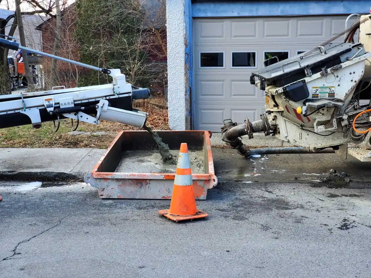 Concrete pump hopper and chute washing out into a CleanSite washout pan on a residential street