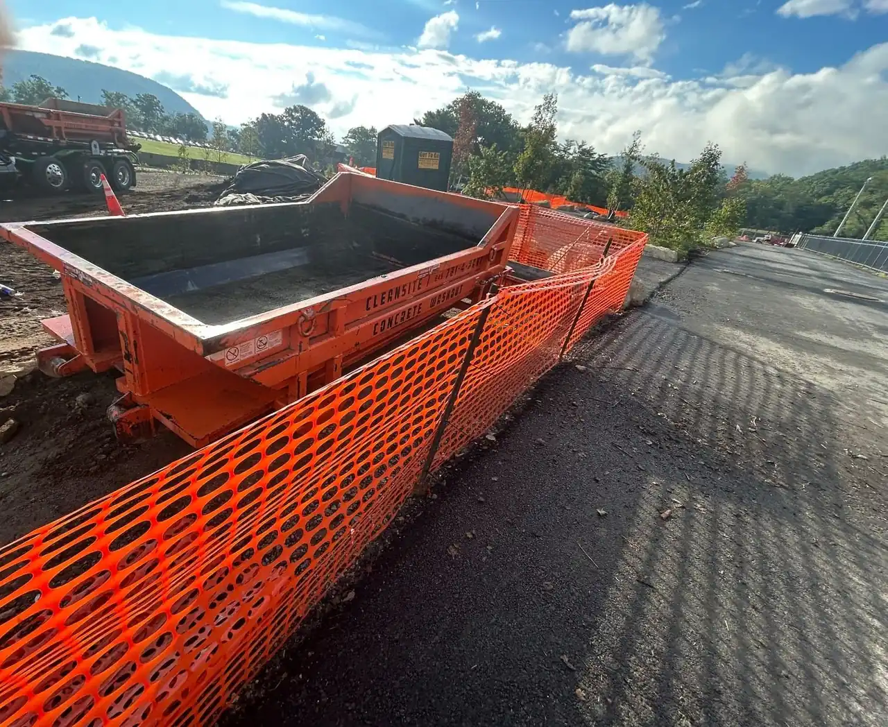 CleanSite washout container behind orange safety fence at the edge of a paved site