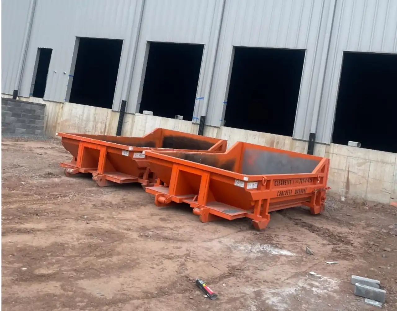 Two CleanSite washout containers beside a warehouse loading dock