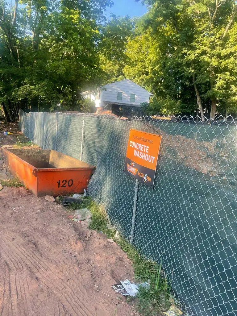 CleanSite washout pan beside a site fence with a concrete washout sign