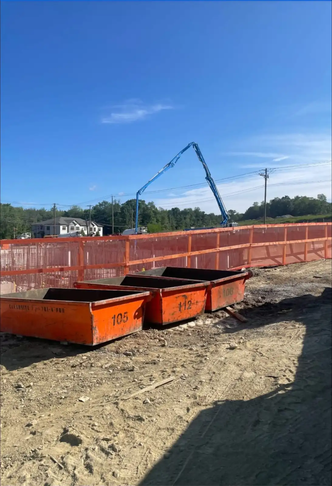CleanSite washout pans behind orange safety fence, with a concrete pump boom in the distance