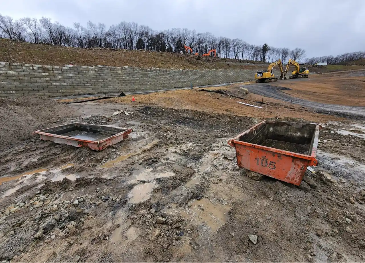 Two CleanSite washout pans on a muddy hillside site