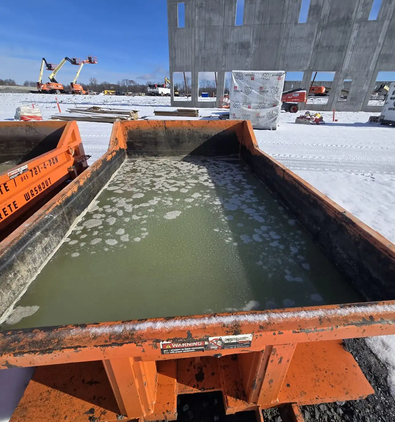 Concrete washout water held in a CleanSite container on a snowy job site